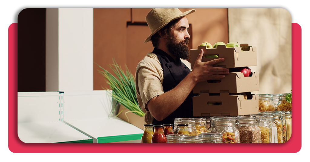 Trabajador con indumentaria adecuada revisando y trasladando en caja de madera frascos de conservas vegetales en una línea de envasado artesanal
