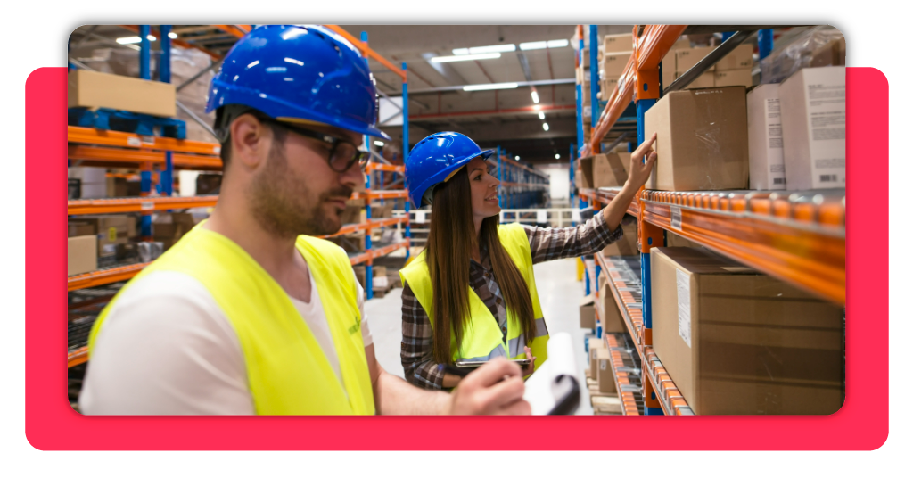 Operarios con cascos y chalecos colaboran verificando inventario de cajas en estanterías, asegurando el control operativo diario y stock con precisión.