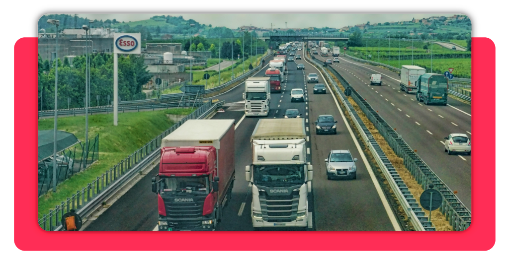 Varios camiones de transporte de mercancía circulan libremente por una autopista durante el día. En los demás carriles hay vehículos pequeños.
