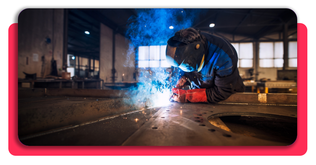 Un técnico cualificado realiza trabajos de ensamblaje y soldadura metálica profesional con equipo de protección individual en un taller industrial en España.